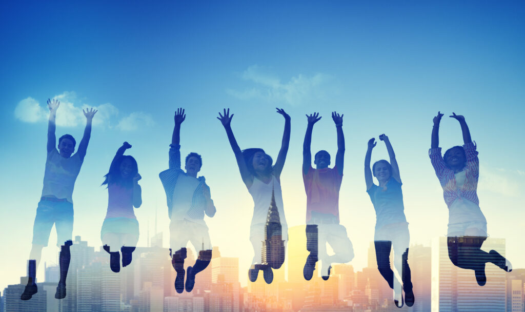 6人の男女がきれいな空の下でジャンプしている